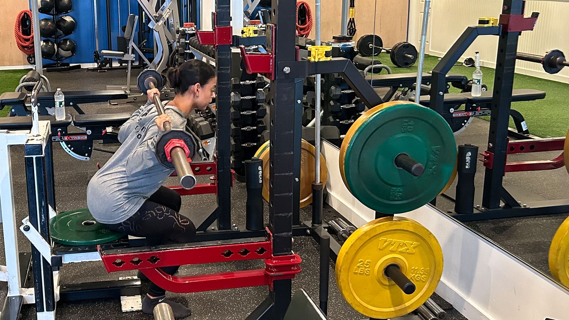 Woman lifting barbell weights during a workout session while personal training at Phys EQ in East Hampton NY 11937