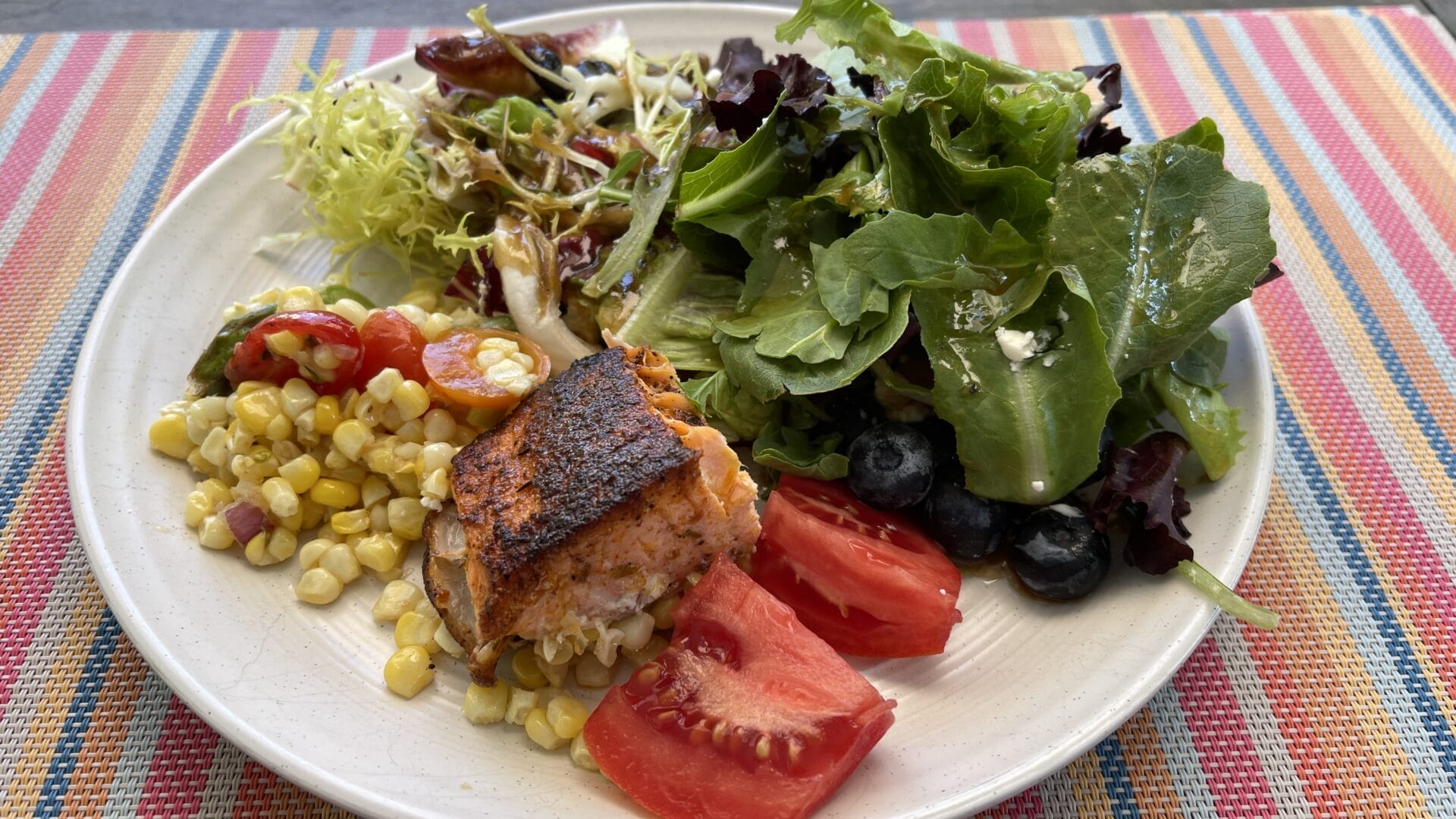 Plate of healthy food including salads, salmon, and a wide variety of vegetables.